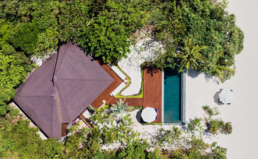 安缦璞乐度假村海滩泳池别墅，俯瞰图显示紫色屋顶建筑、游泳池和翠绿植被。