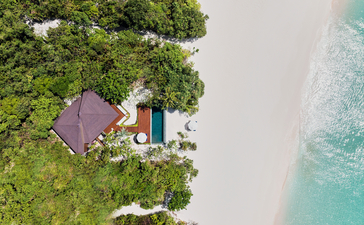 Beach casita at Amanpulo with tropical foliage, white sand, and turquoise waters.