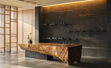 Aman Tokyo spa reception with dark timber shelving and natural wood counter.