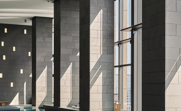 Tall marble columns line the edge of an indoor plunge pool at Aman Tokyo, their reflections mirrored in the still water below.