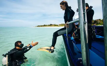 Divers preparing to enter crystal-clear waters at Amanpulo resort.