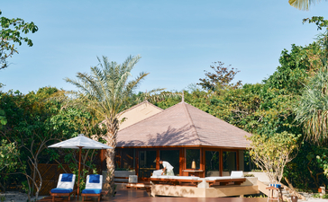 安缦璞乐度假村的沙滩泳池卡西塔住宿，茅草屋顶建筑与游泳池相邻，周围绿化环境优美。