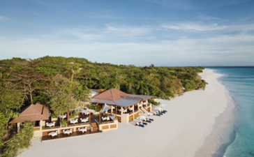 Aerial view of a dining venue nestled along a pristine white-sand beach at Amanpulo, Philippines, with turquoise waters beyond.