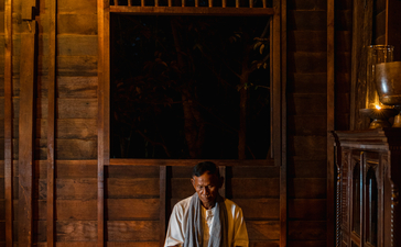 Woman meditating by candlelight in a wooden pavilion at Amansara, Cambodia.
