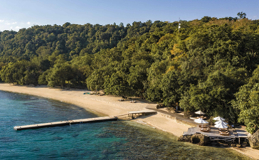 安缦湾澜度假村的海滨，白沙滩与茂密森林相接，碧蓝海水轻拍岸边。