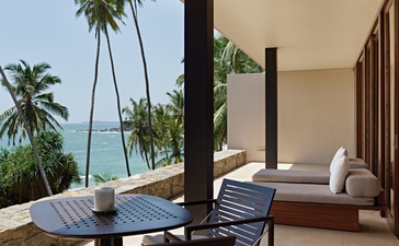 Suite with ocean view at Amanwella, featuring seated area, loungers and Sri Lankan coastline.