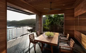 Wooden balcony at Amanoi with dining table overlooking ocean and distant coastline.