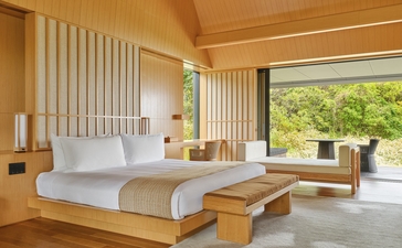 Mori Suite principal bedroom at Amanemu with wooden platform bed, cream furnishings and garden views.