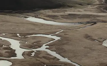 Winding river through arid mountains near Amangani, Wyoming, USA.