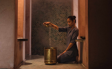 安缦珍纳度假村水疗中心，一位访客在温暖灯光下坐在门框内沐浴。