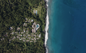 Aerial view of Amankila resort's coastline, where dense tropical forest meets turquoise waters.