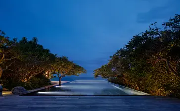 Amanoi resort-ის ოთხ საძინებელი ოკეანის აუზის ოჯახის რეზიდენციის განათებული აუზი საღამოს ღია.
