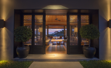 アマノイ リゾートの入口、夜間にライトアップされたガラス扉と、奥に見える温かみのある内部空間。