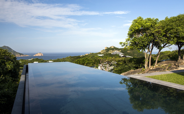 Amanoi's infinity pool overlooking calm waters and forested coastline in Vietnam.