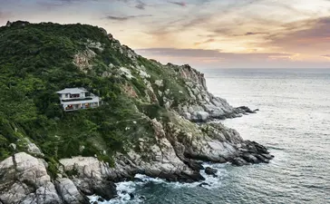 Amanoi perched on a verdant clifftop overlooking the Vietnamese coastline at sunset.