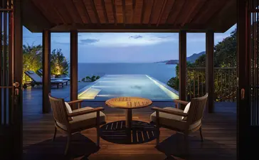 Amanoi swimming pool terrace at dusk, with infinity pool overlooking coastal waters and evening sky.