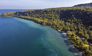 安缦湾澜度假村所在莫约岛的海岸线景观，蓝绿色海水与翠绿森林相接。