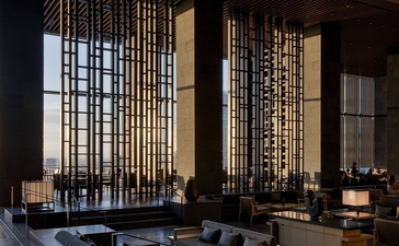 Autumn light filters through wooden screens in Aman Tokyo's serene lounge, with low seating and dark architectural lines.
