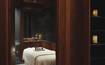 Spa treatment room at Amangani with wooden doorway framing a massage table and warm lighting.