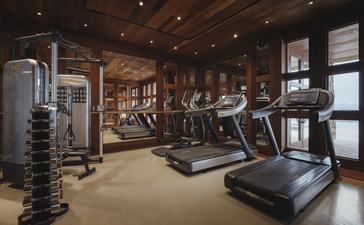 Fitness centre at Amangani with wooden interiors, cardio equipment, and weight racks.