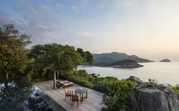 Ocean pool terrace overlooking coastal waters at Amanoi, with dining area and lush vegetation.