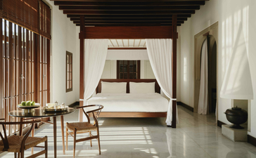 Deluxe sea view pavilion principal bedroom at Amanruya, Turkey, featuring a canopied bed and wooden furnishings.