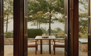 Deluxe Sea View Pavilion balcony at Amanruya with wooden chairs overlooking the Aegean coastline.