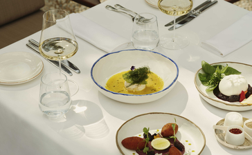 Turkish dishes and place settings at Amanruya's dining venue, featuring plated starters with fresh herbs and vegetables.