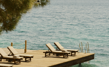Wooden jetty with loungers extending into turquoise waters at Amanruya, Turkey.