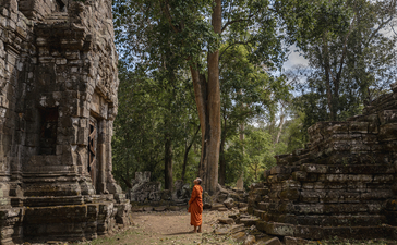 Buddhist monk walking through ancient stone temple ruins at Amansara, Cambodia.