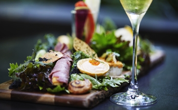 Foret appetiser at Aman Tokyo with cocktails and garnished herbs on dark surface.