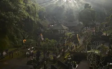 Aerial view of Amandari's terraced gardens and traditional Balinese temple architecture nestled in misty valley landscape.