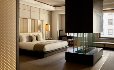 アマン ニューヨークのグランドスイート。ベッドエリアと窓側のラウンジスペースを備えた客室。