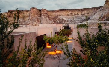 Orchard Suite courtyard at dusk with glowing fire pit, surrounded by desert rock formations at Amangiri.