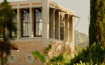 Library Tower at Amanruya, a stone structure framed by cypress trees and green hedges, in Turkey.