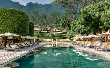 Piscine turquoise entourée de chaises longues et parasols à Amanpulo, un resort aux Philippines.
