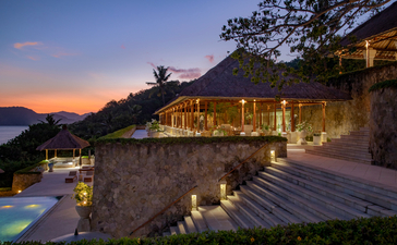 Terrasse d'Amankila au coucher du soleil, avec piscine et architecture en pierre dominant la côte de Bali.
