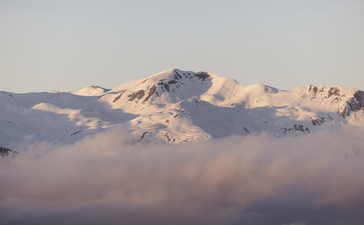 Snow-capped Alpine peaks rising above morning mist at Aman Le Mélézin.