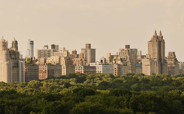 Manhattan skyline viewed from Aman New York Residences, with Central Park greenery in the foreground.