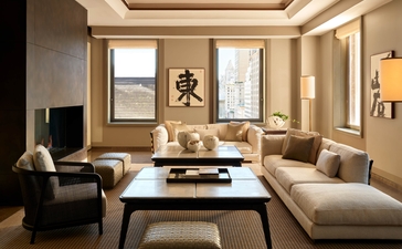 Suite Aman à l'hôtel Aman New York, avec salon aux tons chauds et mobilier contemporain.