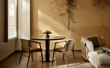 アマン ニューヨークのグランドスイートの居間。木製テーブルと椅子、ベージュのソファが配置され、落ち着いた照明が特徴。