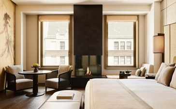 Premier Suite at Aman New York with king bed, seating area, and windows overlooking 57th Street.