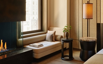 アマン ニューヨークのプレミアスイート。57丁目に面した窓辺に置かれたベンチシート、床から天井までの窓、モダンな照明が特徴。