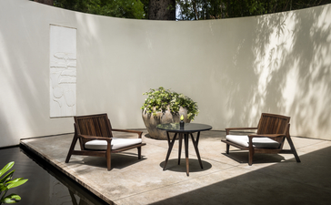 Two leather chairs and a round table in a sun-drenched pavilion at Amansara.