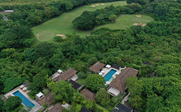Aerial view of Aman Villas at Nusa Dua nestled within lush tropical landscape, featuring villas and golf course.