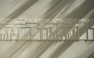 Sunlit corridor at Amansara with wooden beam ceiling casting geometric shadows on white walls.