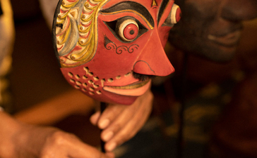 Ornate wooden mask with carved features and golden patina, displayed at Amandari in Ubud, Bali.