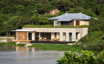Amanoi resort wellness pool villa with lotus lake, aerial view showing modern architecture nestled beside forested hillside, Vietnam.