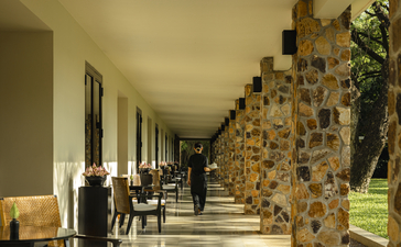 Covered walkway at Amansara with stone columns and seating areas along the colonnade.
