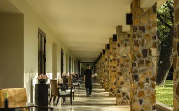 Covered walkway at Amansara with stone columns and seating areas along the colonnade.